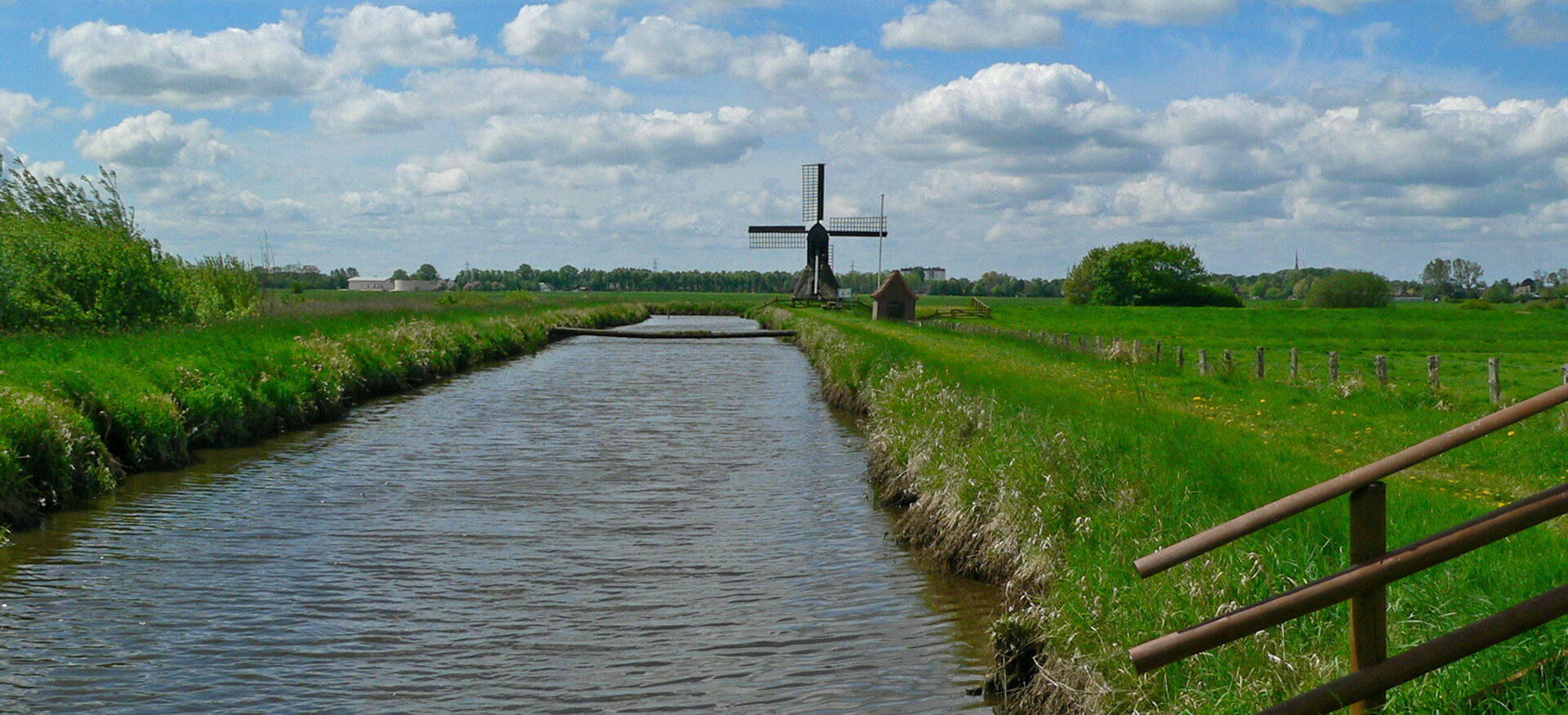 Fluss mit Windmühle in der Distanz