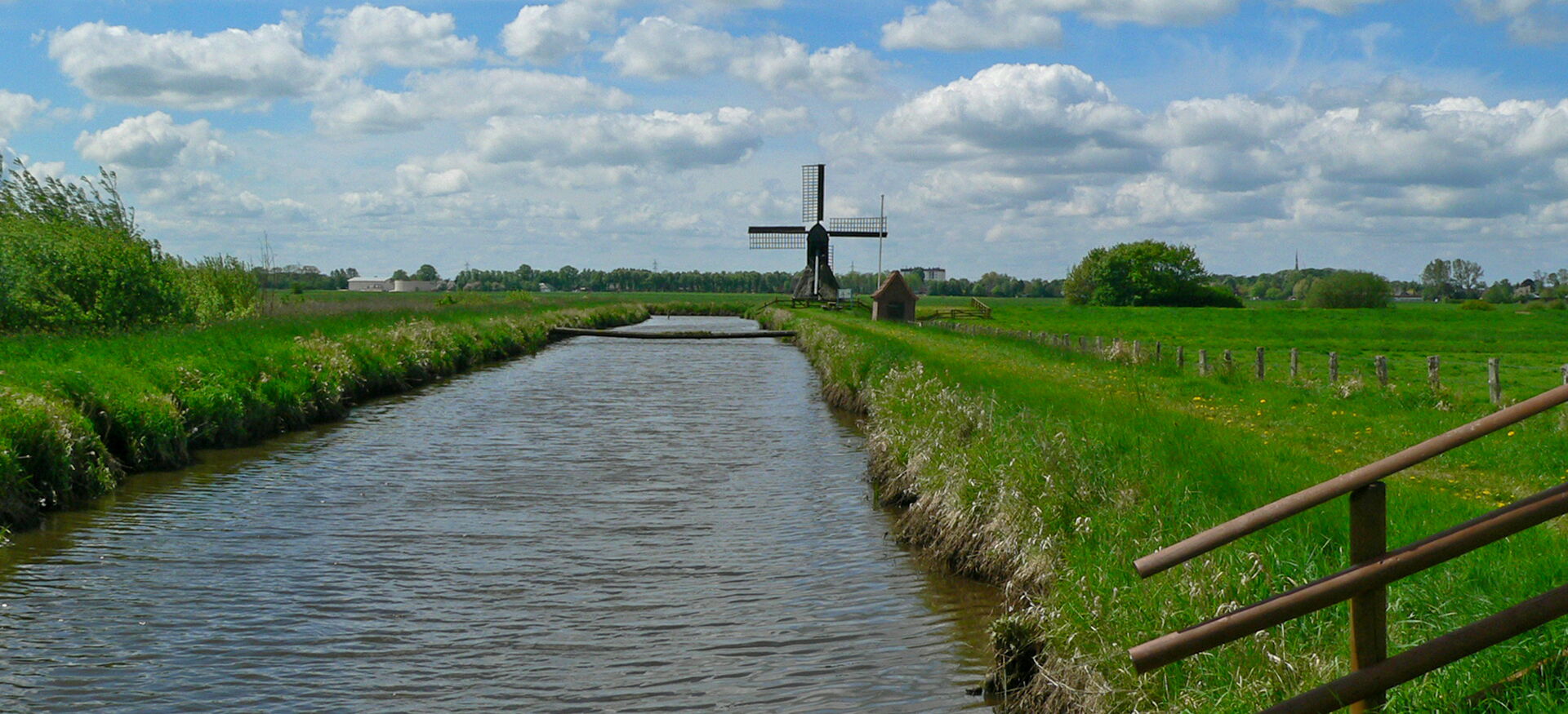 Fluss mit Windmühle in der Distanz
